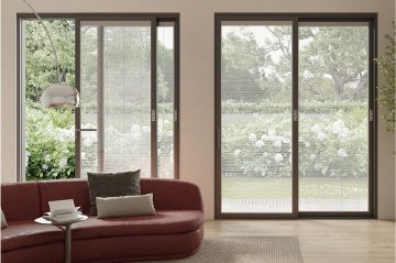 Salón con sofá delante de dos puertas de balcón con persianas integradas